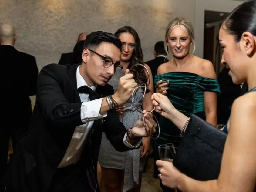 Magician performing a linking rings trick for guests at an evening event